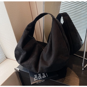 Close-up of black matte suede tote bag showing soft texture and wide shoulder strap detail