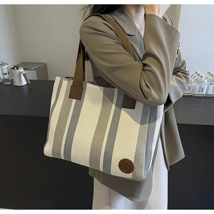 Detailed texture of canvas tote bag with gray stripes and brown fabric shoulder strap
