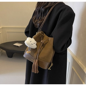Brown suede bucket bag detail with drawstring closure, tassels and a plush cloud charm