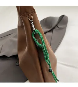 Detail of green woven rope charm with yellow smiley tag on brown litchi leather tote bag