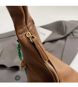 Close-up of smooth gold metal zipper and textured brown leather on a tote bag