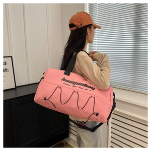 Pink waterproof fitness bag with black drawstrings worn by model in a gym setting
