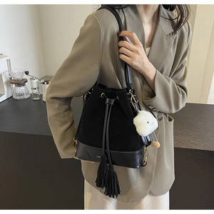 Detail of black drawstring bucket bag with gold lettering and white cloud charm