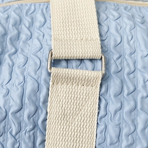 Detail of light blue quilted fabric texture and durable woven shoulder strap buckle