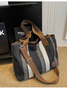 Large striped canvas tote bag with brown straps in a stylish casual home setting