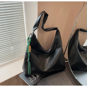 Close-up of black hobo bag with grainy texture and green rope smiley face charm