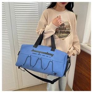 Detail of sky blue sports bag with adjustable black cords and shoulder strap on model
