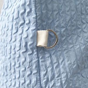 Detailed macro view of light blue seersucker fabric with a beige strap and D-ring hook