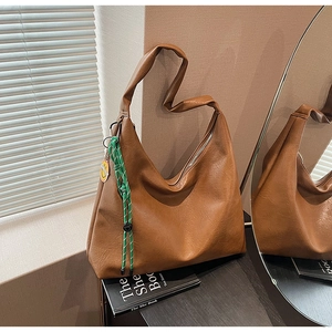 Detailed shot of a brown large hobo bag with green rope charm and yellow smiley tag