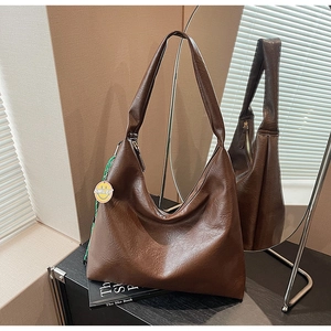 Detail of dark brown leather hobo bag with Smiley charm on a textured shoulder strap