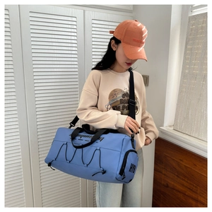 Blue waterproof fitness bag with cross elastic cords shown on a shoulder for scale