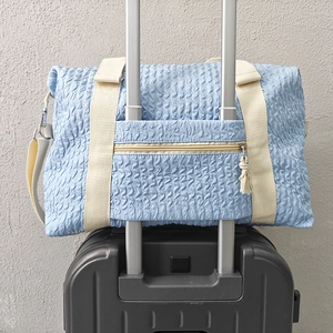 Light blue travel bag with bubble texture on suitcase handle and beige straps