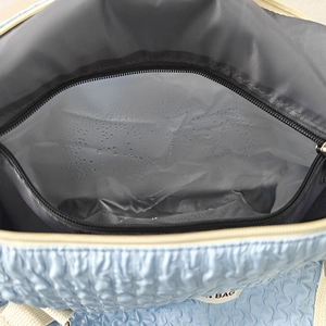 Detail view of the waterproof thermal lining with water droplets in a blue quilted bag