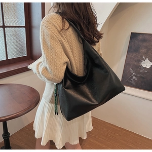 Detailed view of the black oversized tote bag showing textured faux leather and soft drape