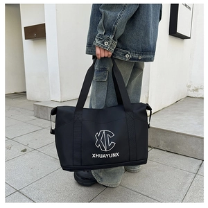 Macro detail of waterproof black travel bag showing reinforced handles and circular XC logo