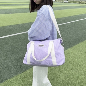 Close-up of light purple quilted duffel bag with Fashion Bag label on a green grass field