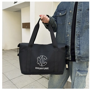 Detail of large black travel duffel bag with shoulder strap and suitcase handle sleeve