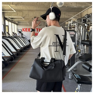 Bolsa de deporte negra con asas dobles y correa ajustable en un entorno de gimnasio