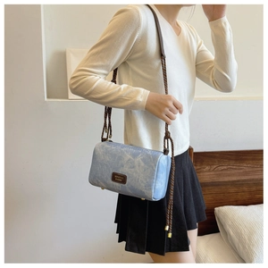 Detail of light blue marble textured envelope bag with woven rope shoulder strap