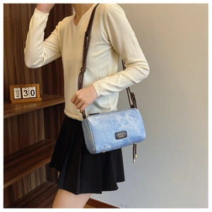 Light blue cylindrical bucket bag featuring woven rope strap shown on female model