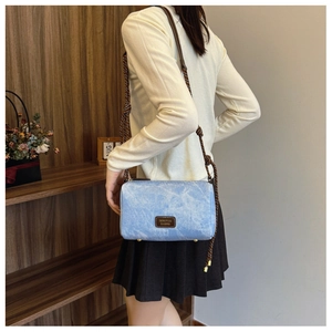 Detail of washed denim shoulder bag with woven rope strap and leather brand patch