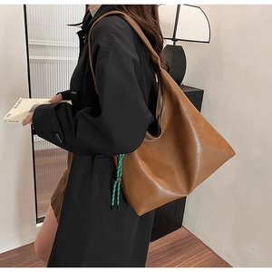 Brown large capacity shoulder tote bag shown on model with stylish woven rope detail
