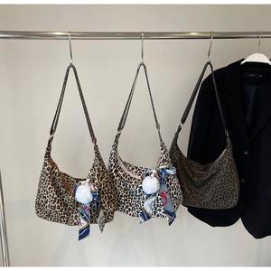 Détails de trois sacs hobo en toile léopard avec des rubans décoratifs et pompons