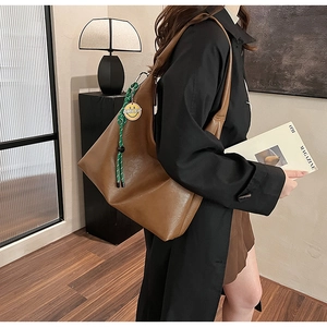 Brown PU leather tote bag with a green rope pendant showing a smiley face on side view