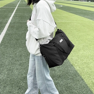 Detailed shot of a black travel bag with textured fabric and fashion label on grass