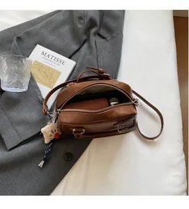 Vue intérieure du sac Boston en cuir marron montrant le rangement et le charme en peluche