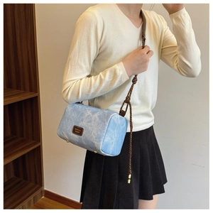 Detailed close-up of light blue cylinder bag with rope strap and textured finish