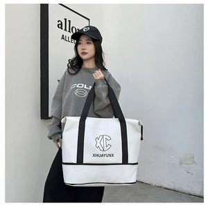 Detail view of large white travel tote with black straps and letter printing
