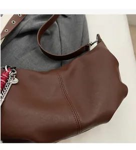 Detail of dark brown faux leather shoulder bag with side braids and metal chain decor