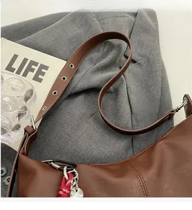 Detailed view of brown PU leather crossbody bag with adjustable wide strap and charm