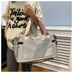 Detail of grey travel bag with pink straps showing durable fabric and brand logo