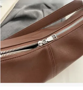 Detail of silver smooth metal zipper and premium stitching on brown leather bag