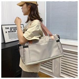 Detail of grey travel duffel bag with pink straps shown in a lifestyle indoor setting
