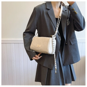 Detail of cream white crossbody bag featuring woven knotted strap and leather logo patch