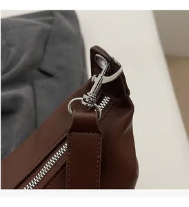 Detail of premium brown faux leather bag featuring glossy silver metal hardware buckle