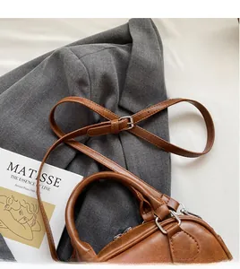 Détail du sac en cuir marron avec bandoulière réglable à côté d'un magazine de mode