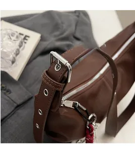Close-up of brown PU leather bag featuring adjustable silver eyelet strap and red cord detail
