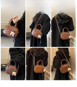 Sac Boston rétro marron porté main et en bandoulière avec un joli pendentif ours