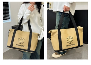 Detail view of large khaki travel tote bag with black XC logo and sturdy handles