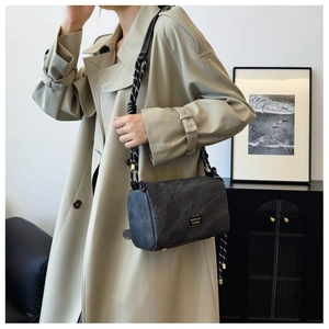 Detail of grey cylinder shoulder bag with textured surface and thick rope strap