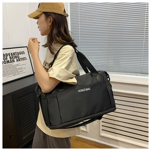Detail of a large black waterproof travel bag featuring reinforced straps and side pockets