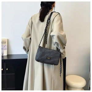 Detail of dark grey pillow bag with marble texture and trendy knotted rope shoulder strap
