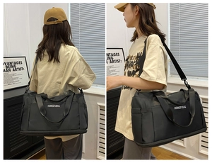 Detail view of large black travel bag with dual handles and padded shoulder strap