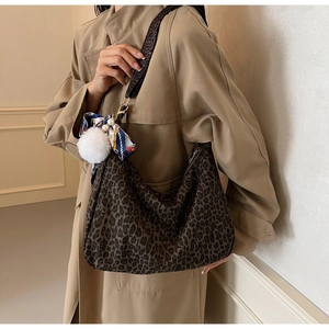 Détail du sac hobo léopard avec pompon en peluche et foulard en soie sur un trench