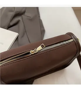 Detail of smooth gold metal zipper on a dark brown matte leather handbag