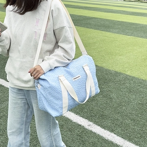Close-up of light blue textured travel bag with white handles in an outdoor setting